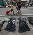 <p>Pessoas cobrem os narizes ao passarem por corpos enfileirados em Tacloban</p>  Foto: AP