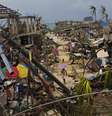 Sobreviventes do tufão Haiyan caminham em meio a ruínas do vilarejo de Maraboth, nas Filipinas   Foto: AP