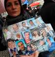 Mulher segura cartaz com fotos de amigos que teriam morrido de câncer durante protesto em Nápoles  Foto: AFP