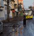 Morador de Nova Iguaçu espera o ônibus em rua coberta por lama, na Baixada Fluminense  Foto: Douglas Viana / Futura Press
