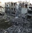 Civil caminha em meio aos escombros de prédios atingidos durante confronto entre rebeldes e forças do governo, em Homs.   Foto: Reuters