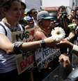Manifestante de oposição dá flor a um policial durante protesto contra Nicolás Maduro  Foto: Reuters