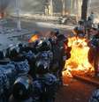 Policiais mantêm posição enquanto são atingidos por fogo causado por coqueteis Molotov atirados pelos manifestantes, em Kiev  Foto: Reuters
