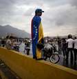 Manifestante vestindo bandeira venezuelana durante protesto da oposição que bloqueou ruas próximas ao aeroporto La Cartola, em Caracas, em 18 de fevereiro  Foto: AP