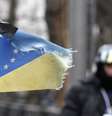 <p>Em gesto simbólico, uma fita preta foi colocada em uma bandeira que combina as bandeiras da Ucrânia e da União Europeia. A simbologia marca um dia de luto nas ruas de Kiev</p>  Foto: Reuters