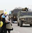 Um comboio militar russo passa por estrada em Simferopol, na Crimeia, neste sábado, enquanto manifestantes contra a guerra protestam  Foto: Reuters