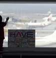 Menina observa os aviões, ao lado de uma placa que diz "temos esperanças", colocada no aeroporto internacional de Kuala Lumpur, na Malásia, nesta segunda-feira, 10 de março  Foto: AP