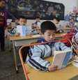 <p>Alunos lêem livros em mesas equipadas com o objetivo de prevenir a miopia, em uma escola primária em Wuhan, província de Hubei, China, em 10 de março</p>  Foto: Reuters