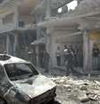 Pessoas se aproximam de local onde dois carros bombas explodiram nesta terça-feira em Homs  Foto: Reuters