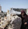 Uma mulher, que foi deslocada devido aos combates entre os rebeldes e as forças do presidente sírio, Bashar al-Assad posa ao lado de sua casa improvisada no sítio arqueológico de Shinshrah, na zona rural de Idlib  Foto: Reuters
