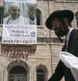 <p>Judeu ultra-ortodoxo é visto passando em frente de um cartaz em homenagem ao Papa, na Velha Jerusalém</p>  Foto: Reuters