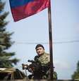 <p>Um separatista pró-russa armado senta debaixo de uma bandeira russa</p>  Foto: Shamil Zhumatov / Reuters
