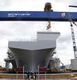 <p>Trabalhadores caminham em frente ao "HMS Queen Elizabeth", o primeiro de dois porta-aviões construídos pela empresa britânica de defesa BAE Systems, no Rosyth Dockyard em Fife, Escócia, em 17 de junho</p>  Foto: Russell Cheyne / Reuters