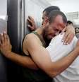 Palestinos choram após encontrarem nome de familiar entre os mortos em bombardeio israelense  Foto: Ibraheem Abu Mustafa / Reuters