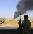 <p>Integrante da milícia Zintan observa um tanque de combustível pegar fogo após o diparo de foguetes em Trípoli, em 2 de agosto</p>  Foto: Hani Amara  / Reuters