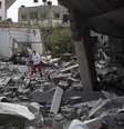 <p>Palestinos caminham entre prédios bombardeados em bairro de Gaza</p>  Foto: Mahmud Hams / AFP