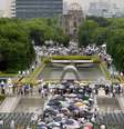 Pessoas enfrentam a chuva para orar pelas vítimas do ataque atômico  Foto: Kyodo / Reuters