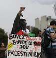Manifestante ergue o braço enquanto segura um cartaz que diz "Beba Coca-Cola, beba sangue de palestinos", em Paris  Foto: Kenzo Tribouillard / AFP