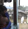 Mulher observa trabalhadores de saúde com roupas especiais em mercado de Monróvia. 17/08/2014  Foto: 2Tango / Reuters