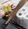 Cliente coloca o dedo sobre um leitor de digitais, para compra de mercadorias no Bicentenário, um supermercado estatal, em Caracas  Foto: Carlos Garcia Rawlins / Reuters