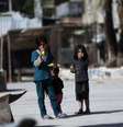 Crianças sírias comem milho em uma rua em Douma, no leste da al-Ghouta, perto de Damasco; o EI fechou escolas ao leste do país nesta sexta  Foto: Bassam Khabieh  / Reuters