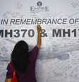 <p>Mulher escreve em painel de mensagem em homenagem a vítimas de voos da Malaysia Arilines MH370 e MH17, em Subang Jaya, em 23 de julho</p>  Foto: Samsul Said / Reuters