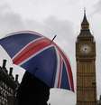 <p>Uma mulher com guarda-chuva nas cores da bandeira do Reino Unido à frente do Big Ben</p>  Foto: Luke MacGregor / Reuters