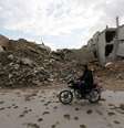 Homem conduz sua motocicleta em frente a escombros de prédios em Maaret al-Naaman, na província de Idlib, Síria. 27/11/2014.  Foto: Khalil Ashawi / Reuters