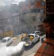 Menino observa trabalhadores aplicando remédio contra mosquito da dengue em rua de Caracas. 22/09/2014  Foto: Carlos Garcia Rawlins / Reuters