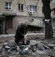 Mulher alimenta pombos diante de casa destruída em Debaltseve, leste da Ucrânia. 05/02/2015.  Foto: Gleb Garanich / Reuters