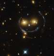 Os olhos do "rosto feliz" são duas galáxias brilhantes distantes, e as linhas que compõem a face e o sorriso arcos criados por um efeito chamado de lente gravitacional forte  Foto: Nasa