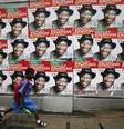 Uma criança corre em frente à propaganda do presidente Goodluck Jonathan para as eleições, que tiveram de ser adiadas devido à violência  Foto:  Akintunde Akinleye / Reuters