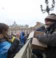 Mauro Casubolo, um sem-teto de Roma, entrega um Evangelho de bolso a uma fiel na Praça de São Pedro, após a oração do Angelus conduzida pelo papa Francisco  Foto: Alessandra Tarantino / AP