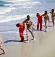 Homens vestidos com roupas laranja são levados para uma praia para serem executados por membros do Estado Islâmico  Foto: Militant Video / AP
