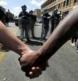 Membros da comunidade dão as mãos em frente a tropas de choque em Baltimore, nos Estados Unidos, nesta terça-feira. 28/04/2015  Foto: Jim Bourg / Reuters