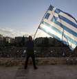 Homem agita a bandeira da Grécia durante manifestação na frente do Parlamento, em Atenas  Foto: Yiannis Liakos / Reuters