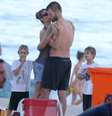 Fernanda Lima beija Rodrigo Hilbert no rosto, enquanto os filhos assistem a cena na praia do Leblon, no Rio de Janeiro, neste domingo (19)  Foto: André Freitas / AgNews