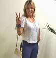 Carla Perez usa calça azul, tipo flare, com blusa branca curta. A calça marca mais do que devia e o comprimento da blusa acaba valorizando demais os quadris. A bolsa pequena e o colar, conhecido como body chain, estão fora de contexto no look  Foto: @carlaperezcpx/Instagram  / Reprodução