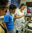 Paola conversa com estudante enquanto cozinha  Foto: ALA/AgNews