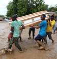 Homens carregam caixão e tentam atravessar o rio La Digue após a derrubada da única ponte pelo furacão Matthew  Foto: EFE
