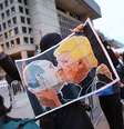 Homem protesta contra Donald Trump segurando cartaz do presidente eleito beijando Putin  Foto: Getty Images