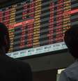 Homens observam painel com dados sobre o mercado de ações  Foto: BBC News Brasil
