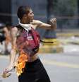 Manifestante atira coquetel molotov contra policiais das tropas do governo venezuelano  Foto: Reuters