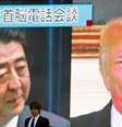 Homem passa diante de telão com as imagens do premiê japonês, Shinzo Abe, e do presidente dos EUA, Donald Trump, em Tóquio  Foto: Reuters