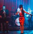 A cantora diante da banda, caracterizada como Winehouse e ‘ao natural’  Foto: João Stark / Divulgação