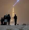 Turistas observam de longe a torre Eiffel cercados pela neve  Foto: Reuters