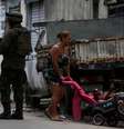 Mulher passa com criança ao lado de soldado do Exército na Vila Kennedy  Foto: Reuters