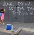 Mulher anda em frente a pichação de protesto em Caracas  Foto: Marco Bello / Reuters