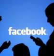 Pessoas utilizam celulares diante de projeção do logo do Facebook em foto ilustrativa  Foto: Reuters