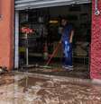 Homem limpa sujeira levada pela enchente no bairro do Cambuci, em São Paulo  Foto: Ananda Migliano/O Fotográfico / Estadão